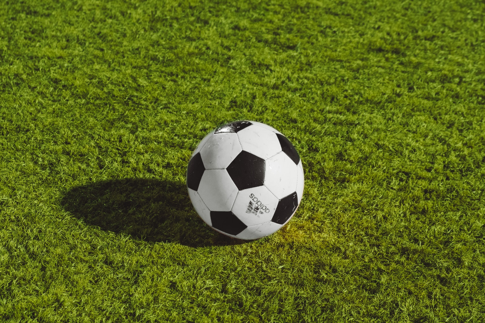 white and black soccer ball on grass field